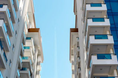 View between the buildings on the sky with a plane flying by.