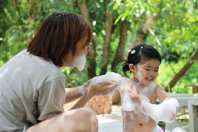 Mother bathing cute daughter at back yard