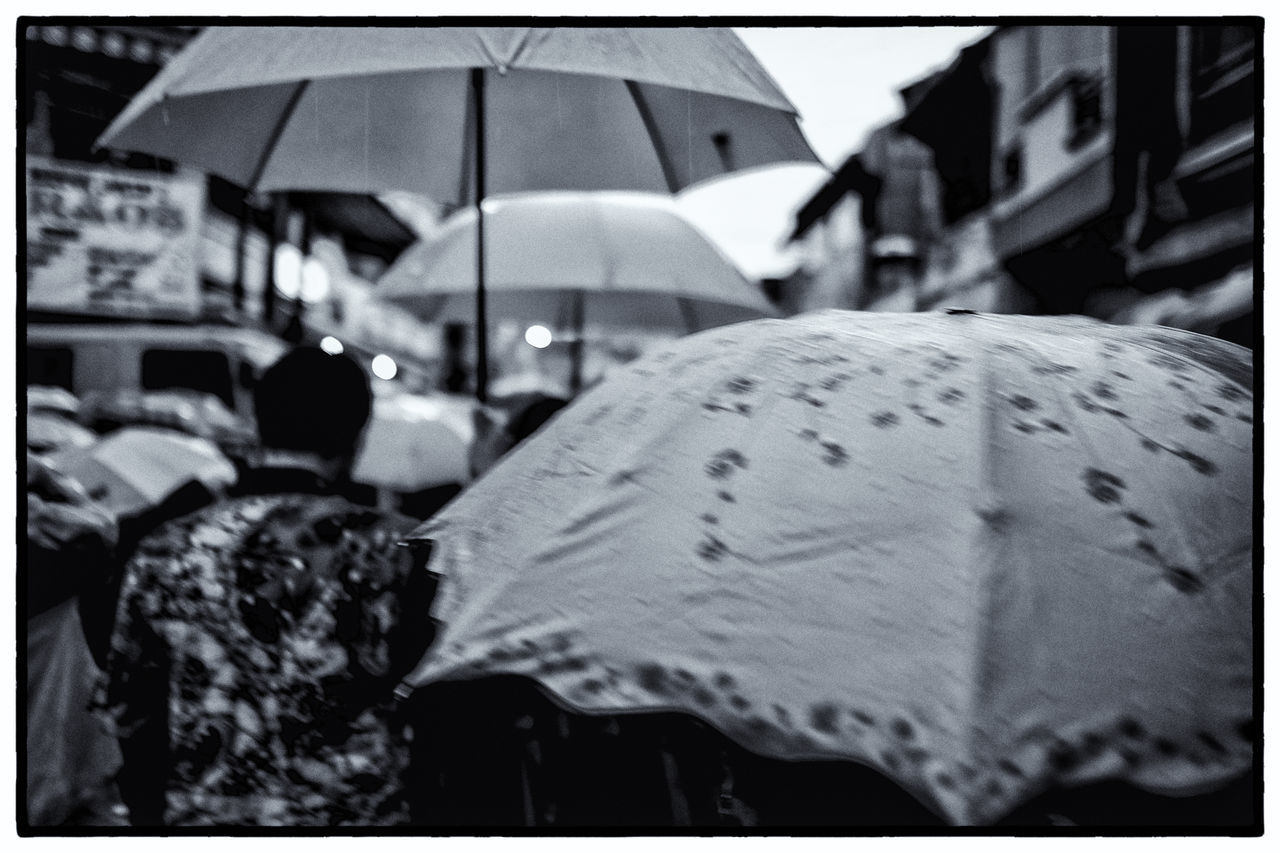 REAR VIEW OF PEOPLE WALKING ON WET RAINY SEASON