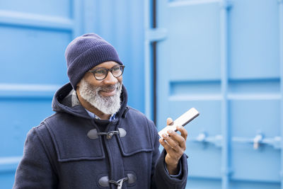 Portrait of smiling man using cell phone outdoors