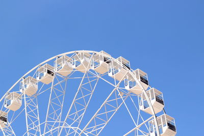 Low angle view of ferris wheel against clear blue sky