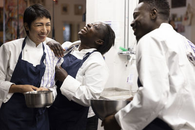 Multiracial chefs laughing while working in kitchen of restaurant