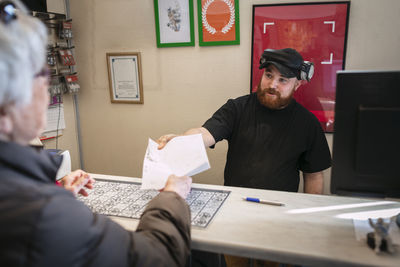 Man giving client invoice for tire change in garage