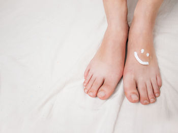 Foot cream on female feet cream in the form of a smiley, close-up, on a white background, foot care