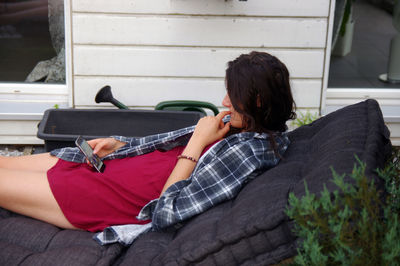 Young woman using phone on sofa