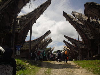 People walking in historic building against sky