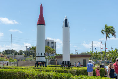 People on field by buildings against sky