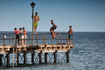 People standing by sea against clear sky