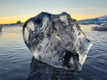 Close-up of frozen sea against sky during sunset