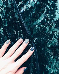 Cropped hand of woman with painted fingernails on sequins