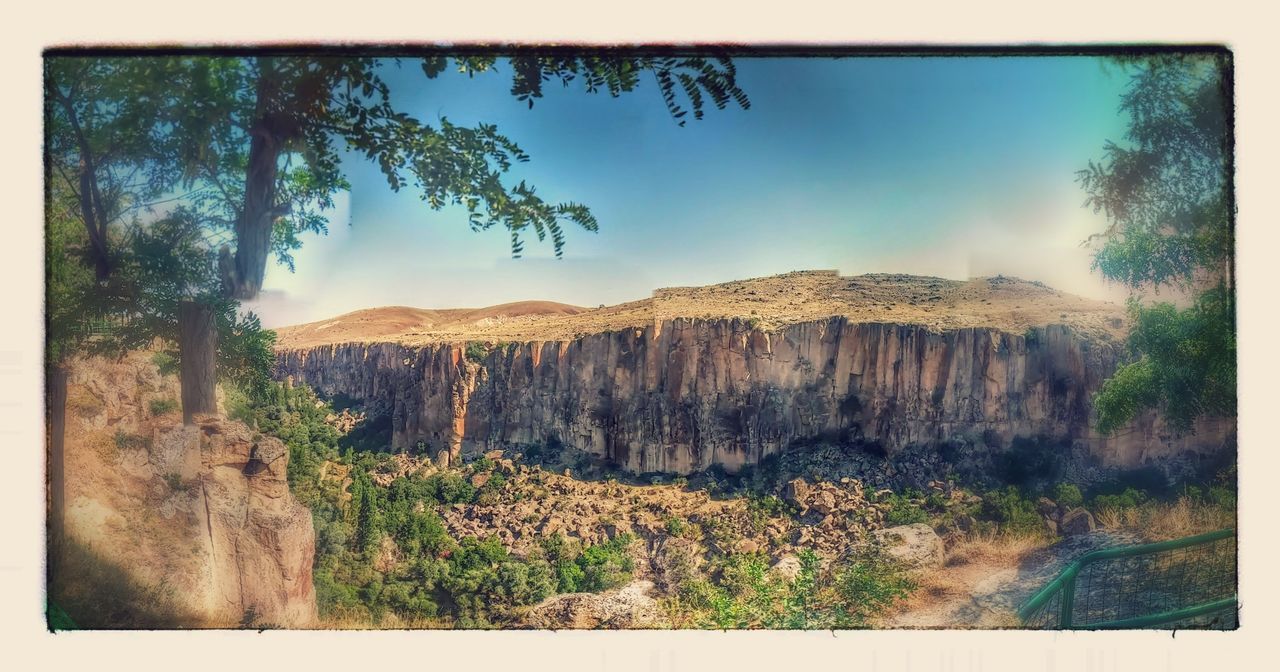 transfer print, mountain, sky, tranquil scene, tranquility, auto post production filter, landscape, tree, scenics, nature, beauty in nature, non-urban scene, blue, mountain range, day, growth, no people, plant, remote, hill