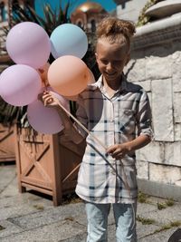 Full length of girl with balloons standing outdoors