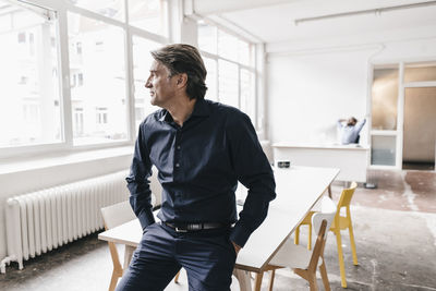 Mature businessman looking out of window in run down office