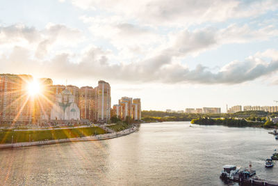 Scenic view of river by buildings against sky during sunset