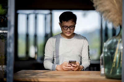 Man using mobile phone while sitting on table