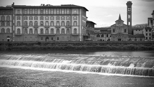 Building by river against sky in city