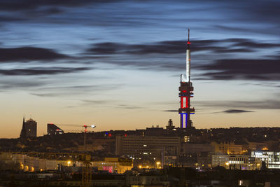 Communications tower in city against sky at night