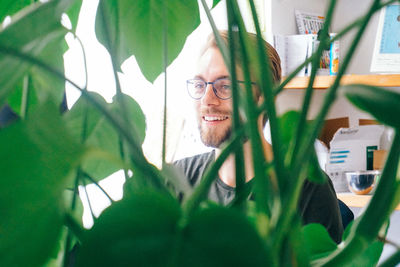 Portrait of young man holding eyeglasses at home