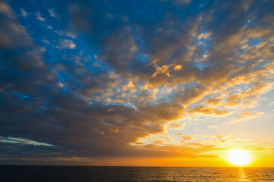 Scenic view of sea against dramatic sky during sunset