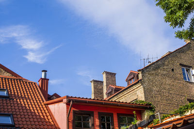 Vintage roofs of houses with windows, balconies and ventilation pipes against blue sky in old town