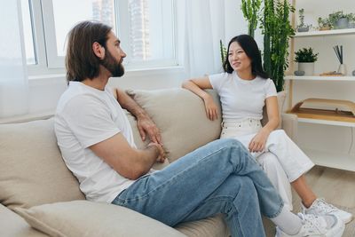 Couple using technologies while sitting on sofa at home