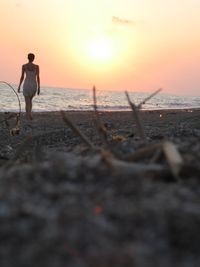 Rear view of man standing on beach during sunset