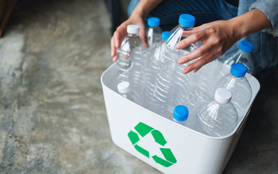 Cropped hand of person cleaning garbage bin