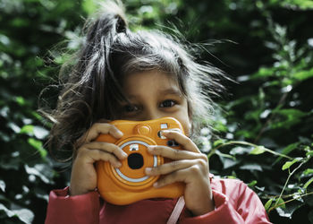Cute little girl snapping a photo with an instax orange camera.