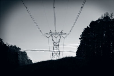 Low angle view of silhouette electricity pylon against sky