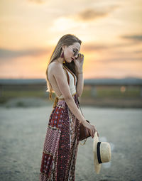 Young woman looking at camera against sky during sunset