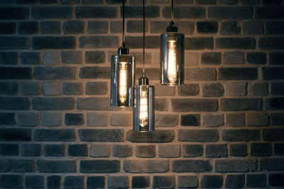 Low angle view of illuminated light bulb against brick wall