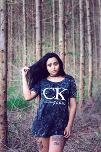 Portrait of young woman standing at forest