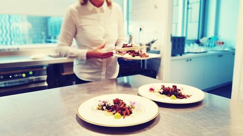 Woman holding food on table in kitchen