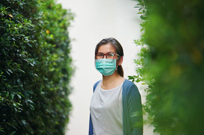 Portrait of young woman against plants