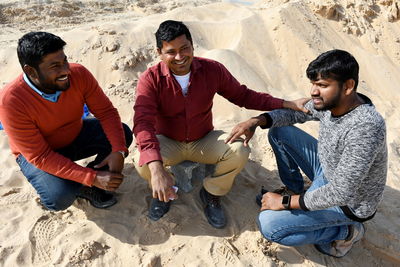 High angle view of friends sitting on beach