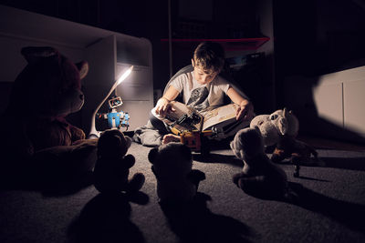 Boy reading book in darkroom