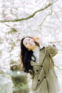 Portrait of young woman standing against bare tree