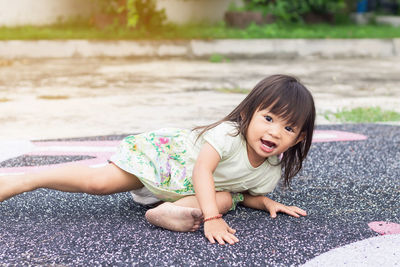 Portrait of cute girl falling in sand at park