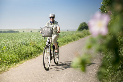 Germany, senior woman riding bicycle in summer