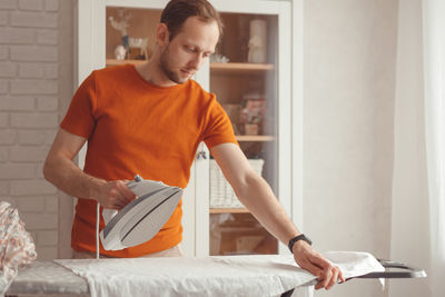 Young man looking at camera while standing on table at home