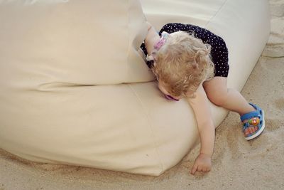 Full length of playful baby girl on couch at sandy beach