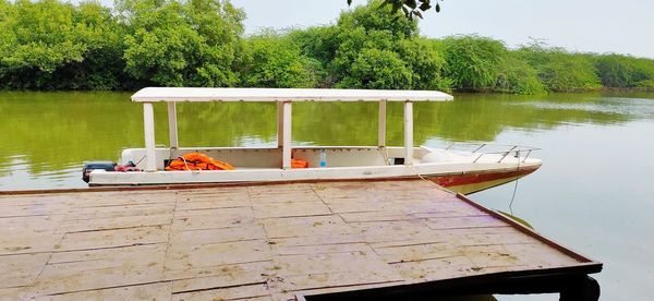 Boat moored on lake against trees