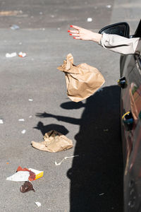 Cropped hand of woman throwing trash from car