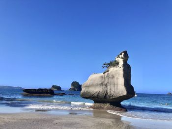 Rock formation on beach against clear blue sky