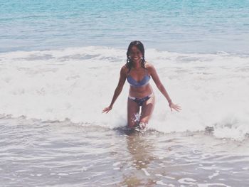 Portrait of smiling young woman wearing bikini standing in sea