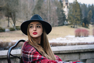 Portrait of woman wearing hat against trees