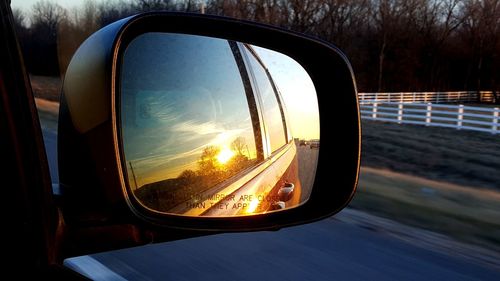 Close-up of side-view mirror against sky