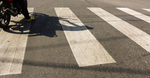 Low section of man on motor cycle over zebra crossing