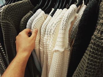 Cropped hand of man choosing clothes from rack