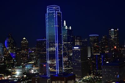 Illuminated cityscape against blue sky